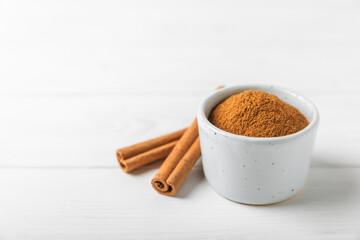 Cinnamon powder on a textured wooden background. Spicy spice for baking, desserts and drinks. Fragrant ground cinnamon. Cinnamon stick. Place for text. Copy space.