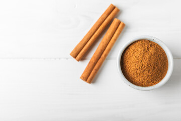 Cinnamon powder on a textured wooden background. Spicy spice for baking, desserts and drinks. Fragrant ground cinnamon. Cinnamon stick. Place for text. Copy space.