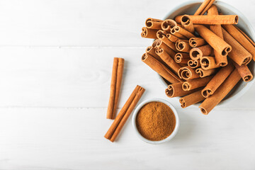 Cinnamon powder on a textured wooden background. Spicy spice for baking, desserts and drinks. Fragrant ground cinnamon. Cinnamon stick. Place for text. Copy space.