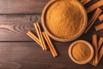 Cinnamon powder on a textured wooden background. Spicy spice for baking, desserts and drinks. Fragrant ground cinnamon. Cinnamon stick. Place for text. Copy space.