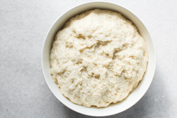 Bread dough that has doubled in size, dough that has risen, proofed dough in a white bowl