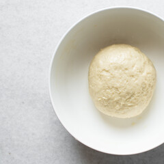 Coco bread dough rising in a white mixing bowl, process of making jamaican coco bread