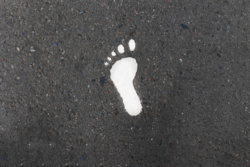 White paint of footsteps on the asphalt road .