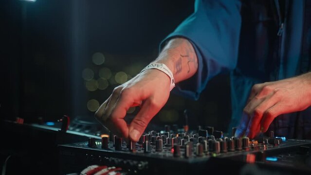 DJ plays set mixing music on audio equipment at techno rave party. Musician hands on turnable closeup. Entertainment event features electronic instruments and musical instruments accessories