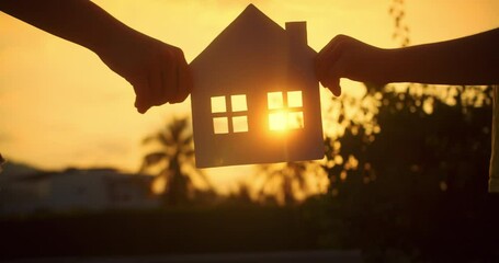 Dream buy house. Paper house hands family, sun shines in window close-up. Hands, paper house at sunset. Symbol home, family comfort. Concept building house family, child. Real estate insurance