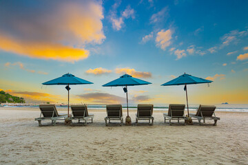 Beaches and sun tables in Thailand,Row of empty sun loungers and orange parasols on the tropical beach at sunset. Vacation in the all inclusive hotel on the Caribbean sea
