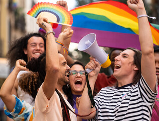 A group of homosexual people excited on a LGBTQ parade jumping and claiming for their rights