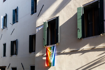 Italian rainbow flag waving from a window in Venice with Pace (peace) written on it; Veneto, Italy