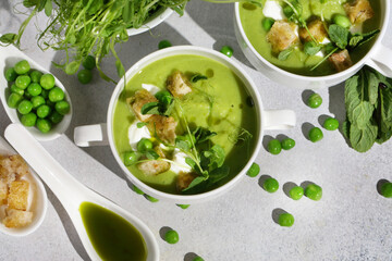 Cool Summer Pea Soup with Croutons, Sour Cream, Fresh Mint, Pea Sprouts, and Parsley Green Oil. Vegetarian Cuisine Idea. Artisanal Photography, Not AI