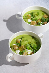 Cool Summer Pea Soup with Croutons, Sour Cream, Fresh Mint, Pea Sprouts, and Parsley Green Oil. Vegetarian Cuisine Idea. Artisanal Photography, Not AI