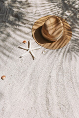 Summer vibes. Broad brim straw hat and sunglasses on a sandy beach. Copy space for text.