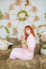 Beautiful redhaired woman with rabbit toy sitting on the haystack Easter holiday concept