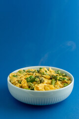 A traditional Alentejo dish, featuring scrambled eggs mixed with vibrant green asparagus. The golden hues of the eggs contrast beautifully with the deep blue background.