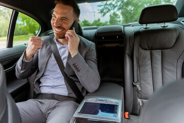 Professional businessman enjoying a conversation on his smartphone during a comfortable car ride