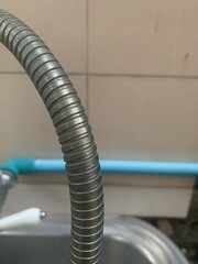 water tap, Shower head and hose with ceramic wall background, closeup of photo, The shower hose is made from threaded stainless steel.