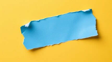   A torn blue paper fragment on a yellow background, resting on a yellow surface