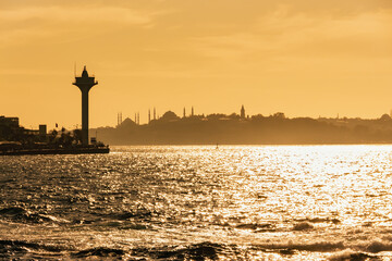 Golden sunset over the Bosphorus with Istanbul's skyline and lighthouse, perfect for travel and...