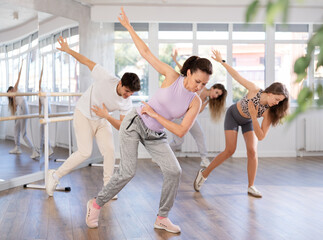 Active middle-aged woman practicing hip-hop dance in training hall during group dancing classes