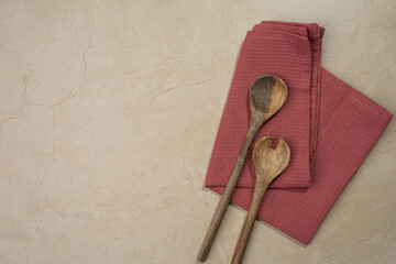 Background with burgundy kitchen towel and wooden spoons, stone table, cooking