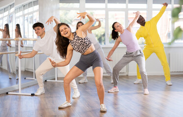 Positive young girl engaged in hip-hop dance together with other attendees of dancing courses