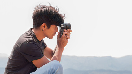 lifestyle concept. Young Latino man using retro camera outdoors