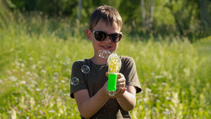 A happy boy is holding a gun with soap bubbles in his hands. Entertainment and recreation.