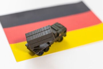 Naklejka premium War, military threat, military power concept. Germany. Tanks toy near German flag on black background top view