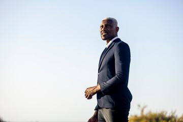 African American businessman gazing into distance on beach
