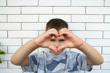 Happy boy making a heart shape with his hands.