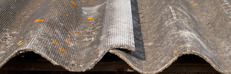 A fragment of the wave slate covering of the old roof. Roof corrugated sheets. Old slate on the...