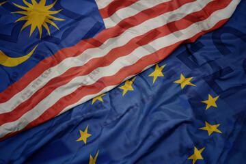 Obraz premium waving colorful flag of european union and flag of malaysia on a euro money banknotes background. finance concept.
