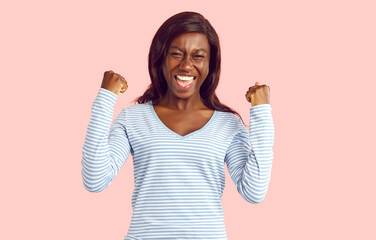 African American woman exclaims Yes isolated on pink background, reveling in the joy of success or...