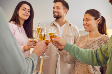 Group of young friends toasting wine glasses and talking standing in a circle together at home. People cheering with glass of champagne celebrating birthday at home party. Celebration concept. - 796964755