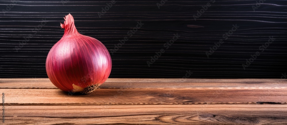 Wall mural Red onion on wooden table with dark backdrop