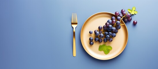 Plate of grapes and fork on blue surface