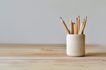 A minimalist pencil holder on a plain wooden desk. - Powered by Adobe