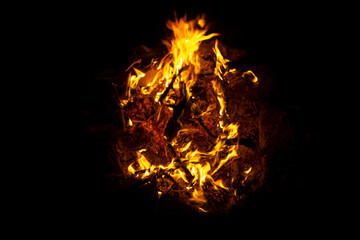 Orange and yellow bonfire flame and hot coals at night, campfire close up on black background. cozy...