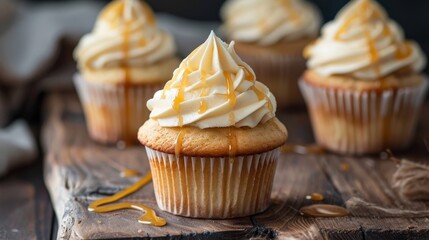 Homemade cupcakes with buttercream frosting and caramel on wooden background