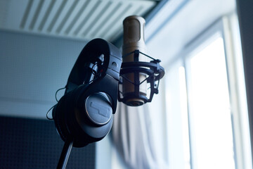 Professional condenser studio microphone and headphones hanging on stand