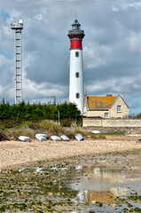 Lighthouse and beach with small boats and pylon at Ouistreham, commune in the Calvados department in the Basse-Normandie region in northwestern France.