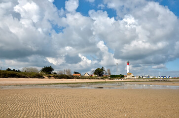 Beach at low tide and lighthouse at Ouistreham with a sky with heavy clouds, a commune in the...