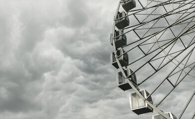 Cabins of a big ferris wheel over dark stormy cloudy sky.