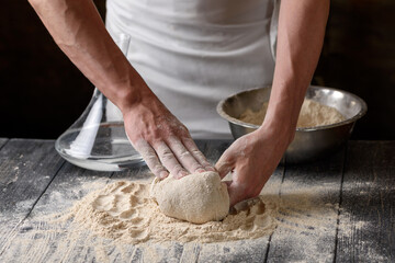 The process of preparing dough. A cook kneads dough from whole grain wheat flour in the kitchen....
