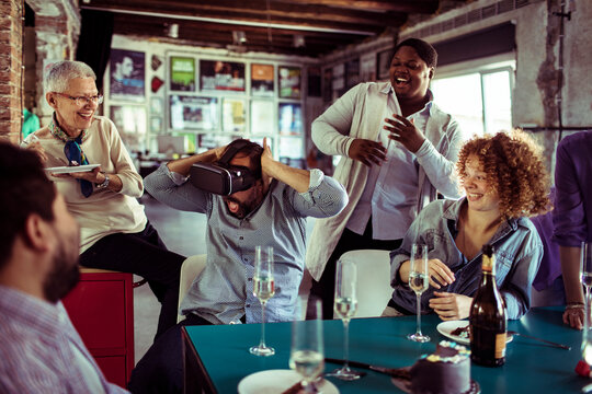 Diverse group of people celebrating a birthday and using a vr headset in a startup company office