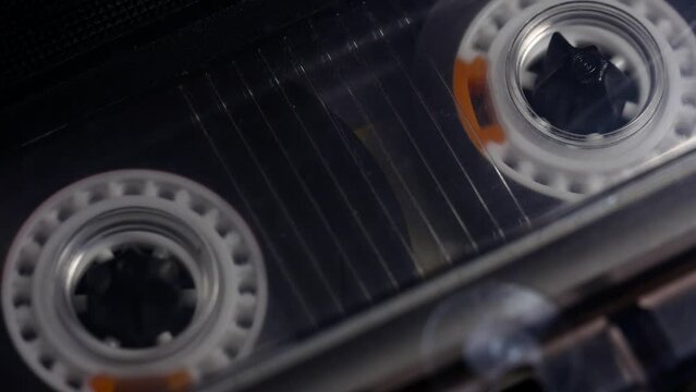 A tape recorder is playing an audio cassette. Close-up. A vintage audio cassette spins on a blank label tape used to record sound in a retro cassette player. Recording of conversations.