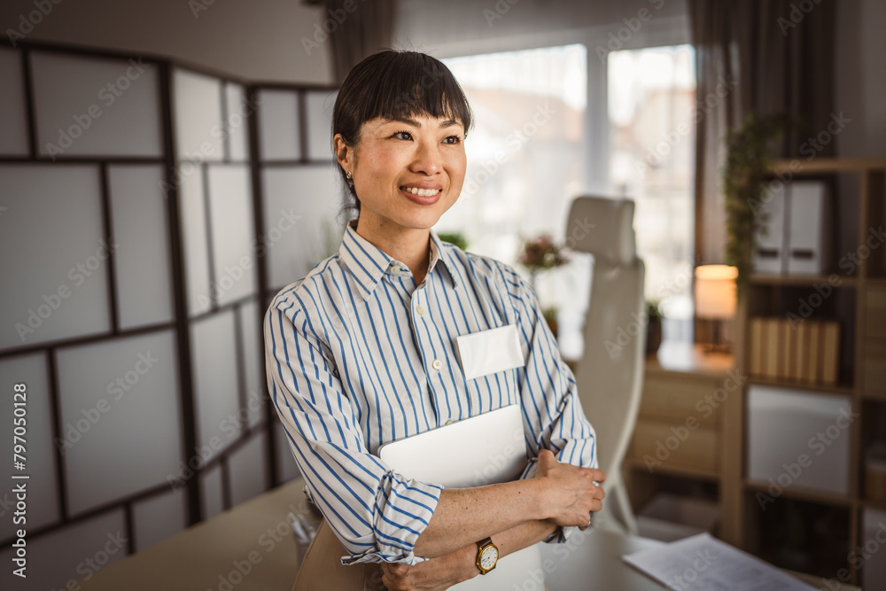 Wall mural Portrait of japanese mature woman hold laptop at the office