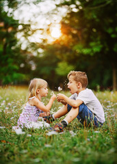Happy children play outdoor with the dandelions. Happy healthy beautiful children with blowball, having fun. Poster.