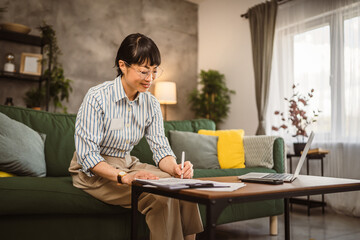 Mature japanese woman with eyeglasses work from home sign document