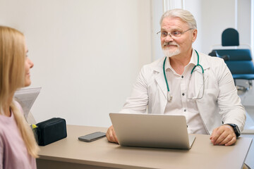 Lady consulting with physician in clinic office - 797058106