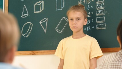 Caucasian boy talking and present idea while standing in front of blackboard with Math theory...